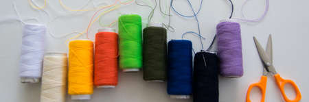 Top view of colorful sewing threads and a scissors on white background, space for  textの写真素材