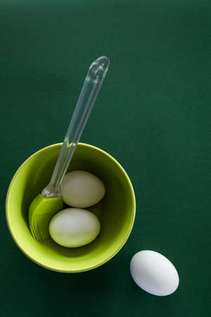 Fresh chicken eggs in ceramic  bowl with pastel colors on deep green background
