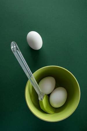 Fresh chicken eggs in ceramic  bowl with pastel colors on deep green background