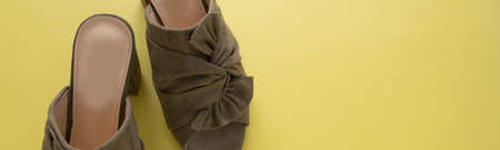 Pair of mules/clogs (military green color) on fresh yellow background, space for textの写真素材