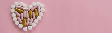 Different medication pills in heart shape on pink background. Healthcare, medical conceptの写真素材