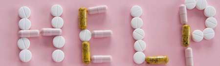 Different medication pills in HELP word shape on pink background. Healthcare, medical concept....
