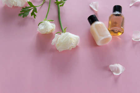 Top view of cosmetic products and delicate flowers on pink background. Wellness beauty treatment. Organic skin care productsの写真素材