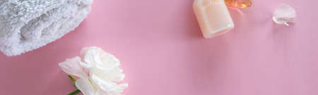 Top view of cosmetic products and delicate flowers on pink background. Wellness beauty treatment....