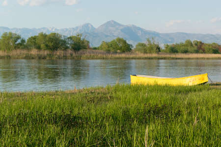 Peaceful river flow and a yellow fishing boat on the grassy shore.Tour tourismの写真素材