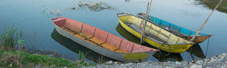 Colorful traditional fishing boats in the river shore with calm waterの写真素材