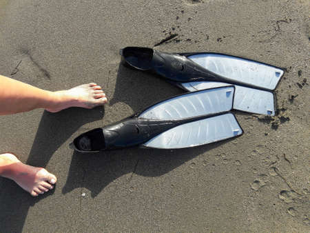 Top view of woman leggs and diving pins on the sandy coastの写真素材