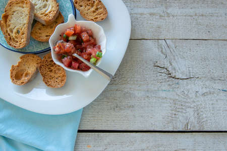 Preparing tasty tomato Italian appetizers -  bruschetta, on slices of toasted baguette, close up...