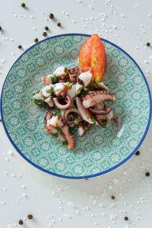 Top view of octopus salad, typical Mediterranean food, on white background with black pepper and sea saltの写真素材