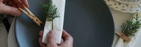 Top view of woman hands preparing and arranging the table for winter holidays. Winter decoration,...