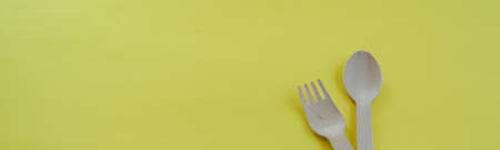 Bamboo wooden spoons and forks on yellow background with space for text. Eco friendly kitchen...