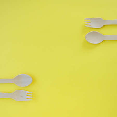 Bamboo wooden spoons and forks on yellow background with space for text. Eco friendly kitchen utensils. Ecological conceptの写真素材