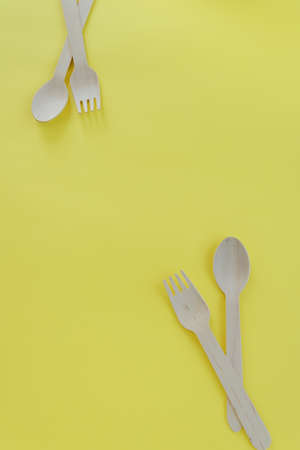 Bamboo wooden spoons and forks on yellow background with space for text. Eco friendly kitchen utensils. Ecological conceptの写真素材