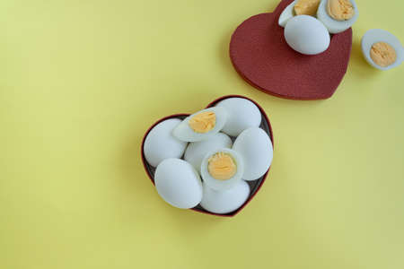 Healthy eating - eggs in heart shaped box on yellow backgroundの写真素材