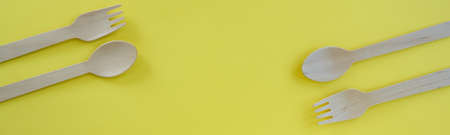 Bamboo wooden spoons and forks on yellow background with space for text. Eco friendly kitchen...