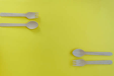 Bamboo wooden spoons and forks on yellow background with space for text. Eco friendly kitchen utensils. Ecological conceptの写真素材