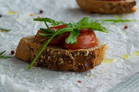 Delicious homemade bruschetta with whole grain bread, grilled tomatoes and fresh arugula. Vegetarian healthy snack, vegan foodの写真素材