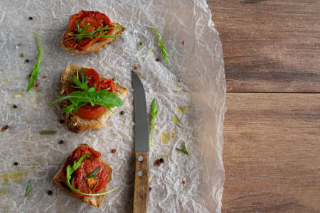 Delicious homemade bruschetta with whole grain bread, grilled tomatoes and fresh arugula. Vegetarian healthy snack, vegan foodの写真素材