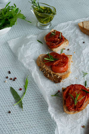 Delicious homemade bruschetta with whole grain bread, grilled tomatoes and fresh arugula. Vegetarian healthy snack, vegan foodの写真素材