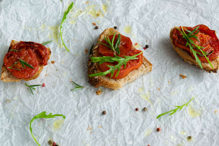 Delicious homemade bruschetta with whole grain bread, grilled tomatoes and fresh arugula. Vegetarian healthy snack, vegan foodの写真素材