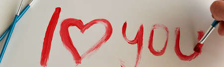 Top view of woman hand painting "I love you" text on white background, artistic creative occupation, love conceptの写真素材
