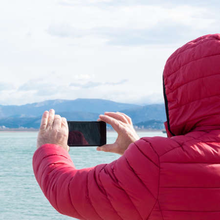 Unrecognisable man taking photos with smartphone. Admiring the nature, wanderlust