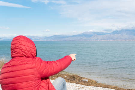 Lonely man sitting on the lakeshore, admiring the nature. Unrecognisable person, wanderlust