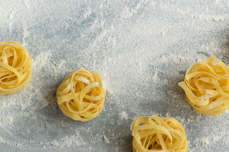 Handmade italian pasta - tagliatelle on grey floury background