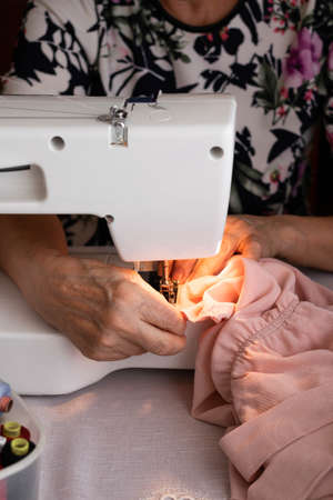 Crop view of woman working in home sewing machineの写真素材