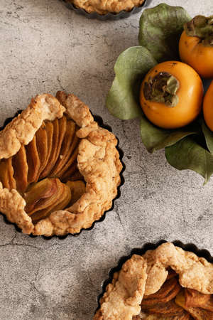 Ready to eat sweet pie with persimmons on gray cement backgroundの写真素材