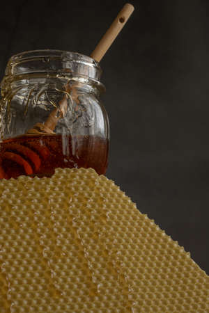 Jar with raw honey and bee comb on dark background, healthy nutrition concept
