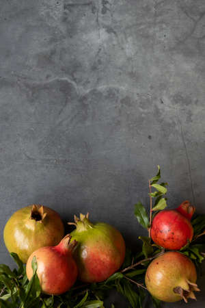 Raw pomegranates on gray background, space for text