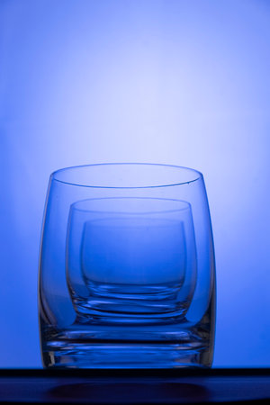 Empty glasses on the table with colorful gradient backlight illuminationの写真素材