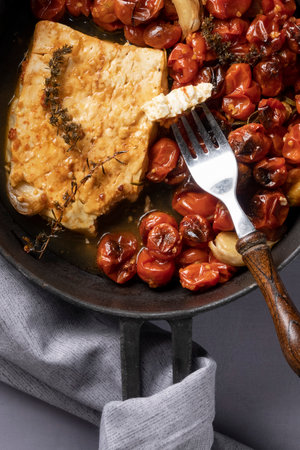 Baked  cherries tomatoes with goat cheese in a pan on the table, healthy eating conceptの写真素材