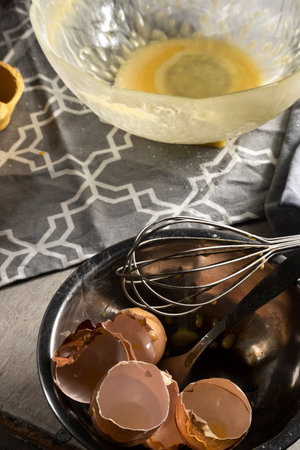 Cooking with eggs, cracked egg shells, used kitchen utensils on the table