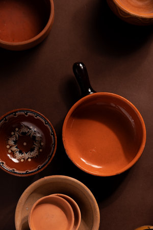 Arrangement of ceramic plates on brown background. Earthenware pottery objects, space for text.の写真素材
