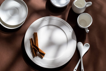 White ceramic dessert plates with cinnamon on brown background. Food concept with space for textの写真素材