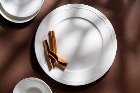 White ceramic dessert plates with cinnamon on brown background. Food concept with space for textの写真素材