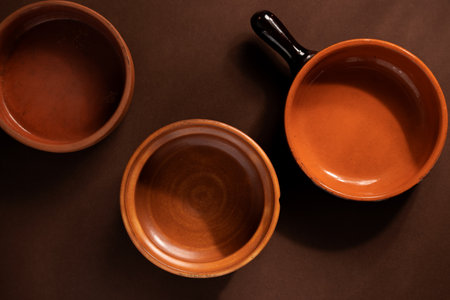 Arrangement of ceramic plates on brown background. Earthenware pottery objects, space for text.の写真素材