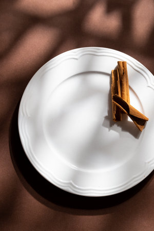 White ceramic dessert plates with cinnamon on brown background. Food concept with space for textの写真素材