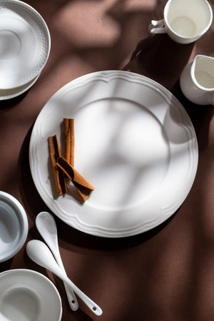 White ceramic dessert plates with cinnamon on brown background. Food concept with space for textの写真素材