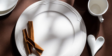 White ceramic dessert plates with cinnamon on brown background. Food concept with space for textの写真素材