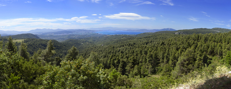 Panoramic view from above on the forests and serpentine of the Greek island of Evia with the sea and clouds on the horizon on a sunny dayの写真素材