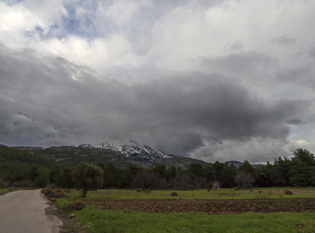 Black storm clouds on a sunny winter day in the forest and mountains on the Greek island of Evia, Greeceの写真素材