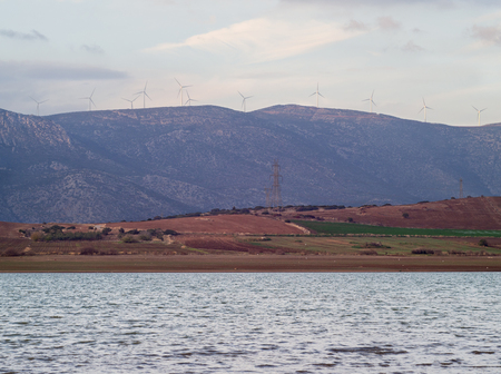 Windmills in the mountains above the lake at sunset in Greece