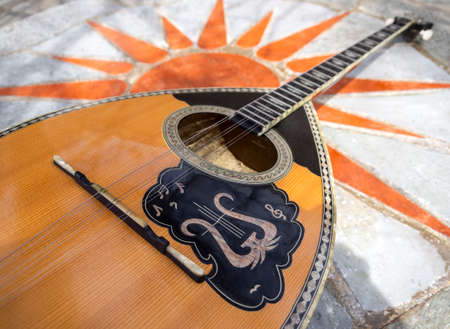 The national Greek stringed plucked musical instrument Bouzouki lies on a marble table in Greece