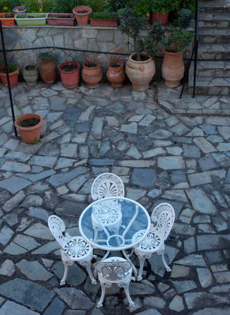White metal table and chairs on the terrace of an old houseの写真素材