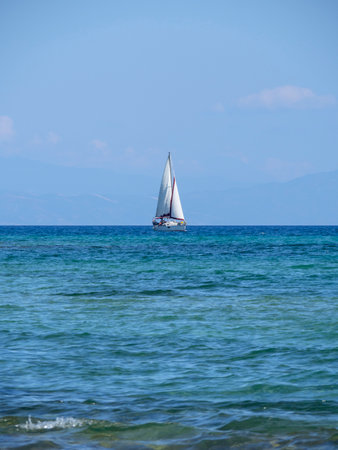 Sailboat in the sea on a background of mountains and blue skyの写真素材