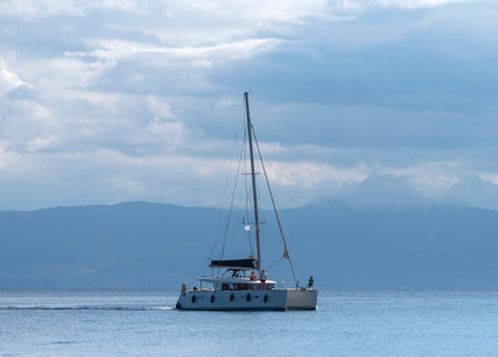 Sailing yacht in the sea on a background of mountains and cloudsの写真素材