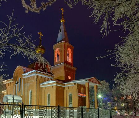 The building of the Orthodox Church at night surrounded by trees in the snow.の写真素材